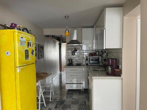 Il comprend une cuisine équipée d'un réfrigérateur jaune et de placards blancs. dans l'établissement Terrace Flat in the Kadikoy Center, à Istanbul