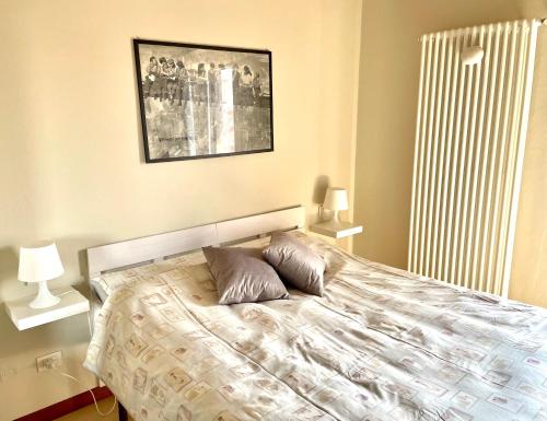 a bedroom with a bed with two lamps and a picture on the wall at Casa Al convento in Savigliano
