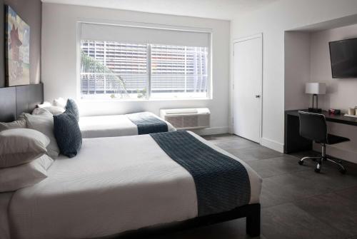 a bedroom with two beds and a window and a desk at MB Hotel, Trademark Collection by Wyndham in Miami Beach