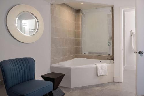 a bathroom with a tub and a chair and a mirror at MB Hotel, Trademark Collection by Wyndham in Miami Beach
