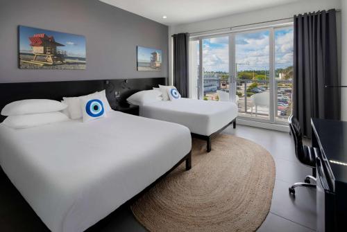 a hotel room with two beds and a large window at MB Hotel, Trademark Collection by Wyndham in Miami Beach
