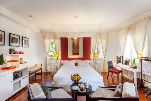 una camera con un letto bianco e una parete rossa di Angsana Maison Souvannaphoum Hotel a Luang Prabang