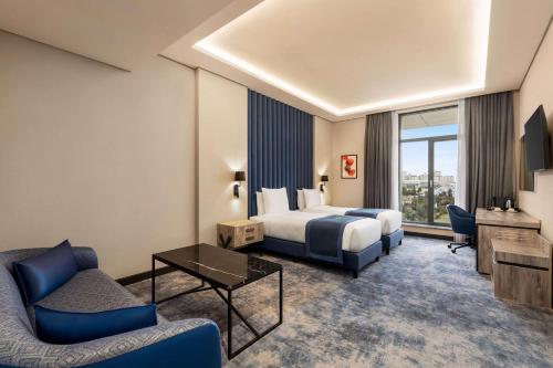 バクーにあるWyndham Garden Bakuのベッド、ソファ、テレビが備わるホテルルームです。