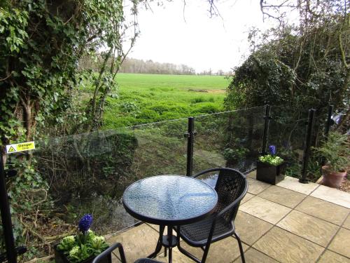 a table and chairs on a patio with a view of a field at The Lily Pad Suffolk in Thornham Magna