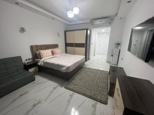 ein Schlafzimmer mit einem Bett, einem Sofa und einem TV in der Unterkunft Luxury Apartment Panorama Naama Heights Resort in Sharm El Sheikh