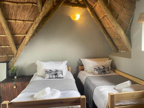 two beds in a attic room with wooden ceilings at Ingwe Bush Lodge in Hoedspruit