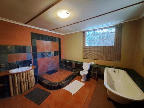 a bathroom with a tub and a toilet and a sink at Stone Meadows Country Estate-NV51 in Magaliesburg