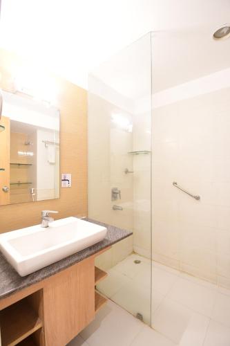 uma casa de banho com um lavatório e uma cabina de duche em vidro. em The Xen Suites, Kolkata Airport em Calcutá