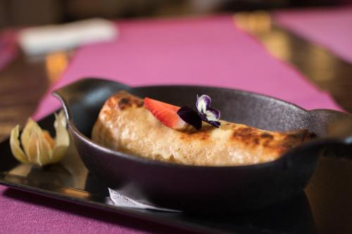 a piece of food in a black pan with a strawberry on it at Hotel Roberto Slanic Prahova in Slănic