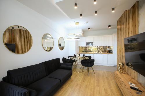 a living room with a black couch and a kitchen at Apartament Gdynia Arena in Gdynia