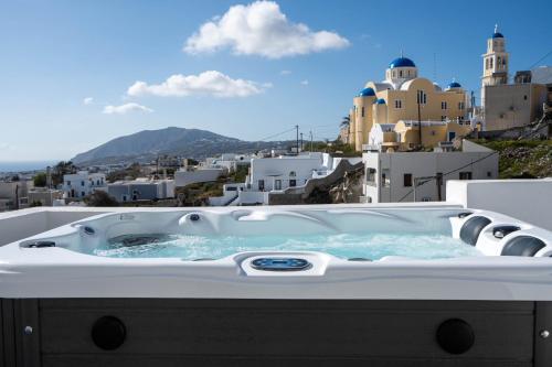 a jacuzzi tub with a view of a city at Cycladic Suites & Spa in Fira
