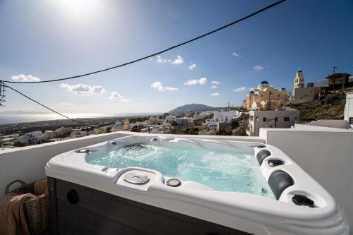 a hot tub on a balcony with a view of a city at Cycladic Suites & Spa in Fira