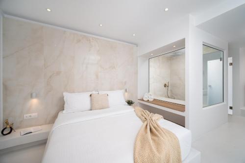 a white bedroom with a large bed and a mirror at Cycladic Suites & Spa in Fira