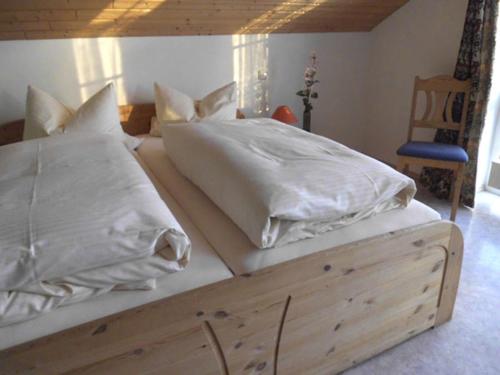 a large bed with white sheets and pillows on it at Gästehaus am Rathaus, Mehrbettzimmer 2 in Hohenpeißenberg