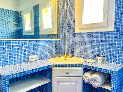 La salle de bains est pourvue de carrelage bleu, d'un lavabo et d'un miroir. dans l'établissement Saint Tropez Bay Charming villa with sea view, à La Croix-Valmer