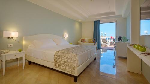 een slaapkamer met een bed en uitzicht op de oceaan bij Hellenia Yachting Hotel & SPA in Giardini Naxos