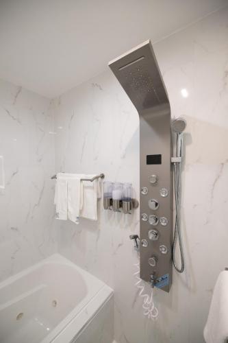 a white bathroom with a tub and a shower at Omeo Suites in Alhambra