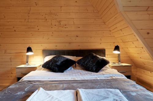 a bed in a wooden room with two lamps at Domek Apartament u Wilków na wyłączność Zakopane in Zakopane