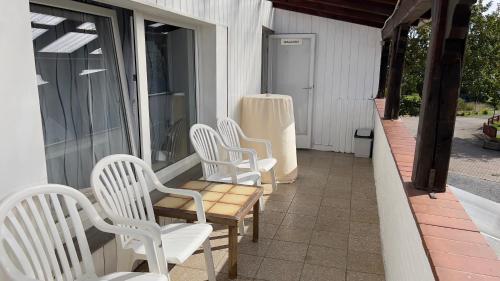 four white chairs and a table on a porch at Pension Reiter in Blomberg