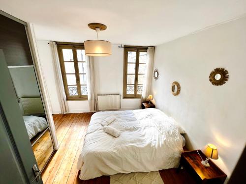 a bedroom with a white bed and a mirror at La persienne Bleue - Coeur historique de Mortagne au Perche in Mortagne-au-Perche