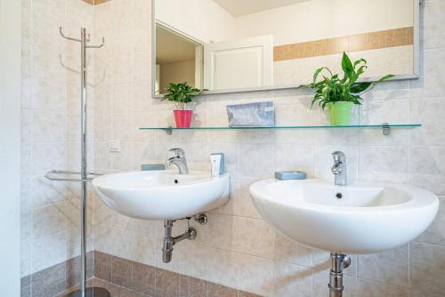 a bathroom with two sinks and a mirror at Broletto Park Apartment - Affitti Brevi Italia in Lecco