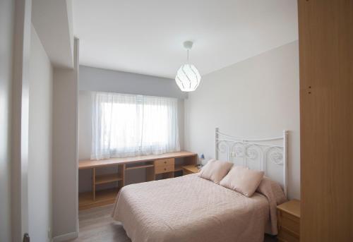 a bedroom with a bed and a desk and a window at AMPLIO APARTAMENTO EN BURELA in Burela de Cabo