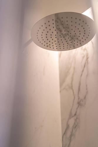 a shower head in a bathroom with a marble wall at Solferino34 in Milan