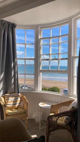 a living room with windows with a view of the beach at Whitecliff Guest House in Weymouth
