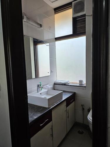 a bathroom with a sink and a mirror and a toilet at Family 3bhk Home stay! in New Delhi