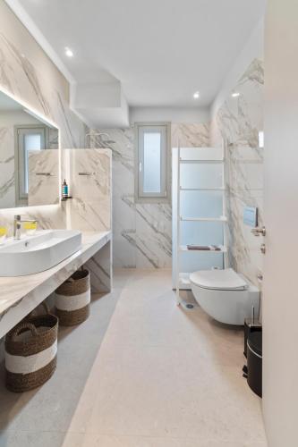a white bathroom with a sink and a toilet at SuiteHome Villas with Private Pools by Explore Andros in Andros