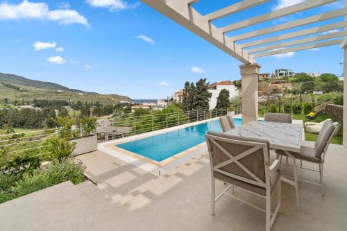 a patio with a table and chairs and a swimming pool at SuiteHome Villas with Private Pools in Andros