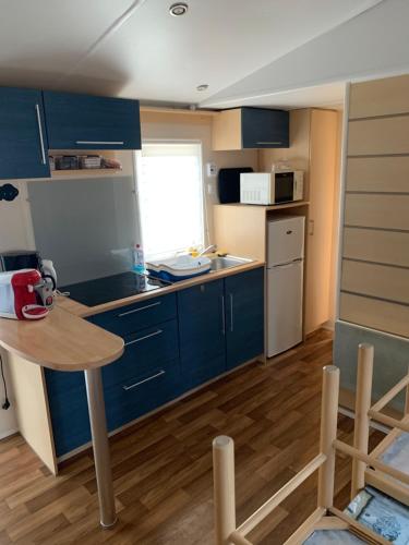 a kitchen with blue cabinets and a table in a room at Chez Nathalie mobil home chauffé et climatisé in Boofzheim