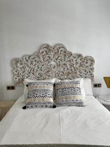 a white bed with a silver headboard and pillows at A Das Marias GALLERY in Ourense