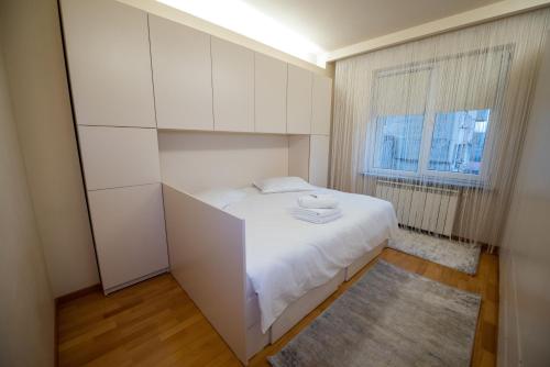een kleine slaapkamer met een wit bed en een raam bij Cozy Apartment in Suceava in Suceava