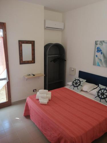 a bedroom with a red bed with towels on it at b&b Le Rocce in San Vito lo Capo