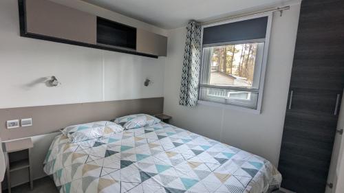 een kleine slaapkamer met een bed en een raam bij Mobilhome Eleganzia 713 Bonne Anse Plage in Les Mathes