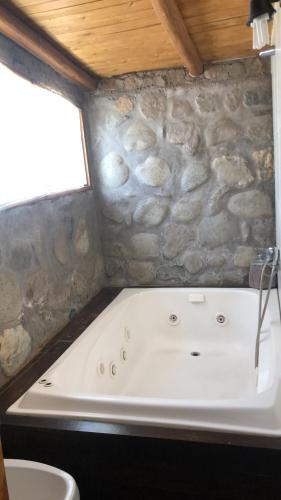 uma banheira na casa de banho com uma parede de pedra em Refugio Inka Habitación Suite em Malargüe