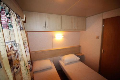 ロクブリューヌ・シュル・アルジャンにあるHarbers zonvakanties chalets met airco camping Leï Suves Roquebrune sur Argensのベッド2台と白いキャビネットが備わる小さな客室です。