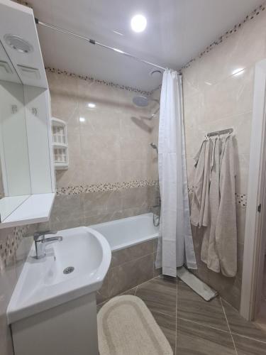 ein Badezimmer mit einem weißen Waschbecken und einer Dusche in der Unterkunft New Аpartment Balti in Bălţi