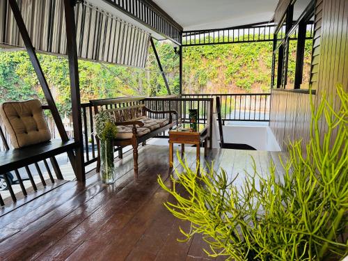 a porch with a couch and chairs on a wooden floor at @Home Hostel Wua Lai in Chiang Mai