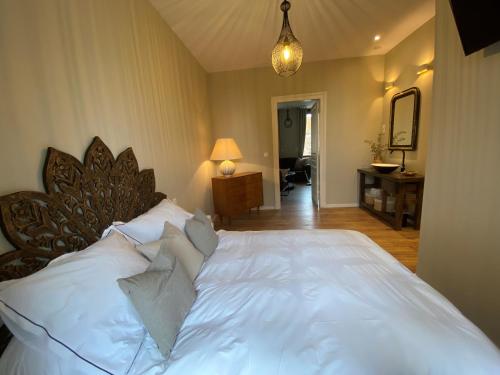 une chambre avec un lit avec des draps blancs et des oreillers dans l'établissement Appartement Complet Rez-de-chaussée, à Sains-Richaumont