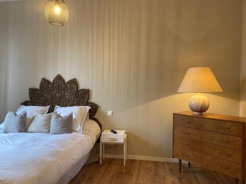 a bedroom with a bed with a lamp and a dresser at Appartement Complet Rez-de-chaussée in Sains-Richaumont