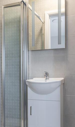 a bathroom with a sink and a shower with a mirror at Tramore Beach Room 5 in Waterford