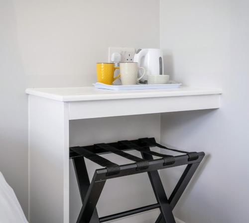 Una mesa blanca con un estante y tazas. en Tramore Beach Room 5 en Waterford