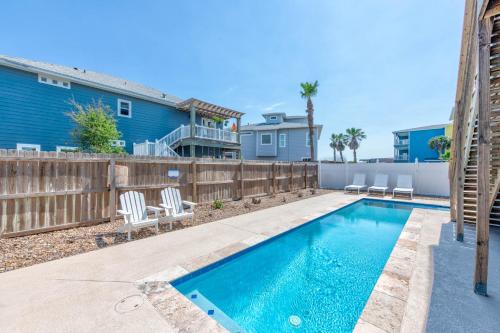 een zwembad in een achtertuin met stoelen en een hek bij Big Blue in Port Aransas