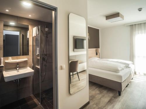 a bathroom with a sink and a bed and a mirror at Motel Waidhofen an der Thaya in Waidhofen an der Thaya