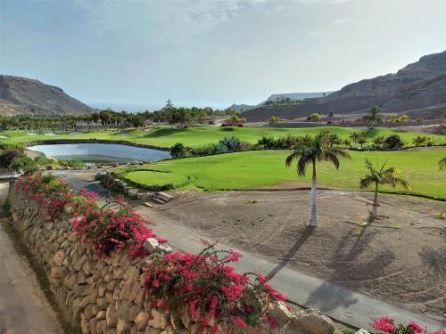 un campo de golf con una palmera y un estanque en Villa Playa Tauro - Luxury bungalow with pool, en Mogán