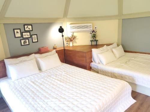 a bedroom with two beds with white sheets at Olive Vanilla Pension in Gyeongju