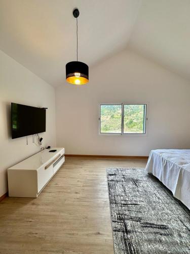 a white room with a bed and a flat screen tv at The Passion Fruit House in São Vicente