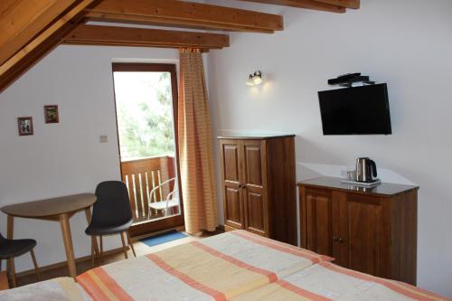 a bedroom with a bed and a table and a television at Penzion Úsmev in Arnutovce